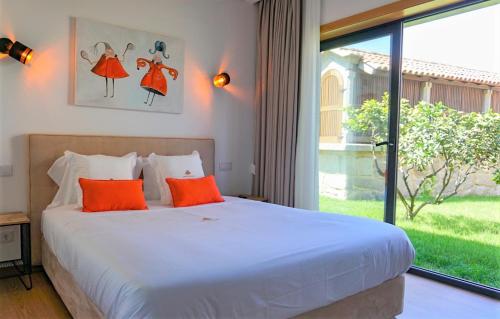 a bedroom with a bed with orange pillows and a window at Quercia Houses in Viana do Castelo in Viana do Castelo