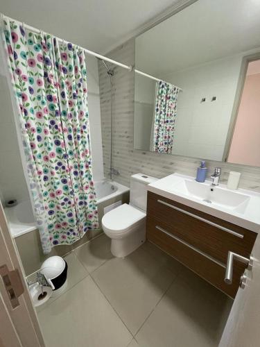 a bathroom with a toilet and a sink and a shower curtain at Departamento Tucapel 1 centro de Concepción in Concepción