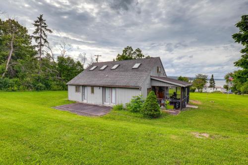 a small white house in a grassy field at Keuka Lake Cabin with Boat Dock Access and Fire Pit! in Hammondsport