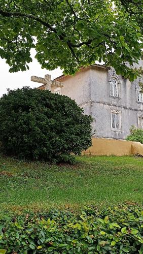 a church with a cross in front of a bush at O Cantinho Alojamento Local in Luso