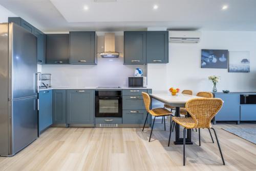 a kitchen with blue cabinets and a table and chairs at Deluxe Seaview Apartment in St. Julianʼs