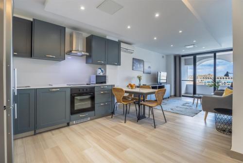 a kitchen with blue cabinets and a table and chairs at Deluxe Seaview Apartment in St. Julianʼs
