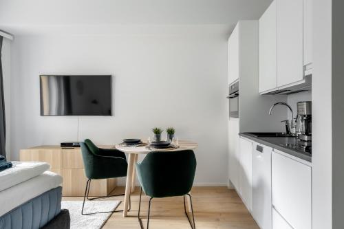 a kitchen with a small table and two green chairs at Upea yksiö joen läheisyydessä in Turku