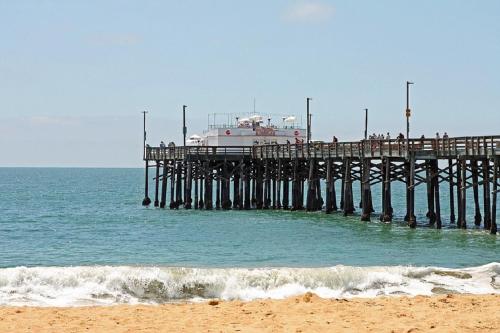 a pier with a boat sitting on top of the ocean at 3112 W Oceanfront A in Newport Beach