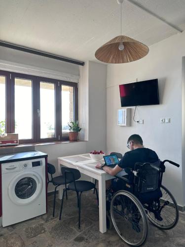 a man in a wheelchair sitting at a table with a laptop at Marvel Sea View 3 in Akrogiali