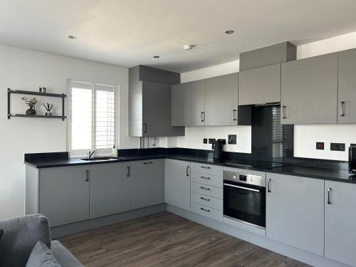 a kitchen with white cabinets and black counter tops at Millicent Room in Littlehampton