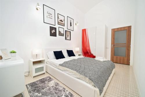 a white bedroom with a bed and a red curtain at Central Liberty Square JF Kennedy apartment - By OpenHouse in Timişoara