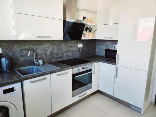a kitchen with white cabinets and a sink at Wellness Apartmány EMPORIO in Loštice