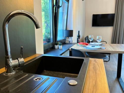 een keuken met een wastafel en een tafel met wijnglazen bij Apartamenty La Venda in Darlowko