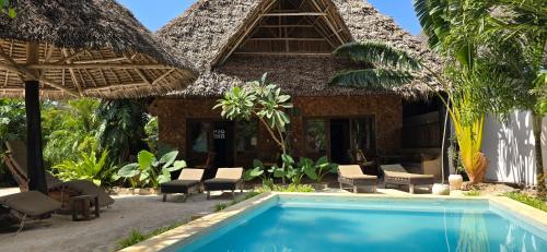 a resort with a swimming pool in front of a building at Salama & Mbuyuni Bungalows in Matemwe