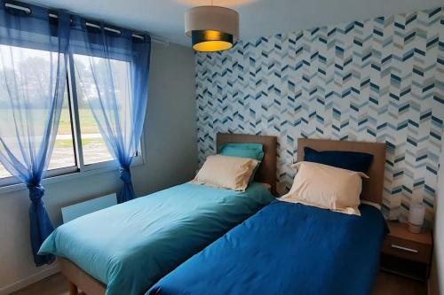 two beds in a bedroom with blue sheets and a window at Gîte au bord du lac - 4-10 pers - La Roche sur Yon in La Roche-sur-Yon