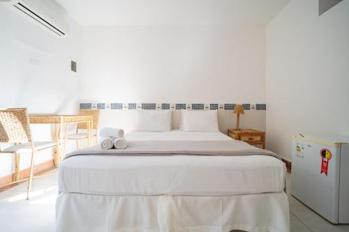 a bedroom with a white bed with towels on it at Pousada Porto Fino in Cabo Frio