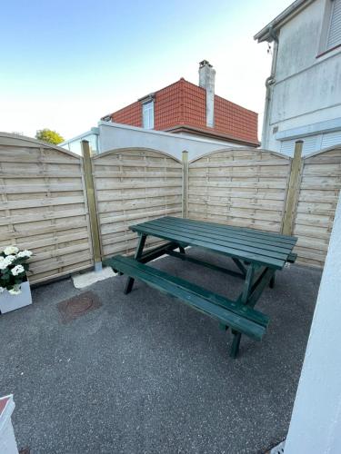 un banc de pique-nique vert devant une clôture dans l'établissement Le nid des hirondelles, à Cucq