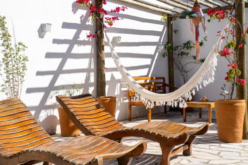 a porch with two chairs and a hammock at Pousada Porto Fino in Cabo Frio