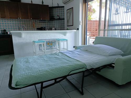 a bed in a kitchen with a couch and two chairs at Casa Vacanze Margarita in SantʼAlessio Siculo