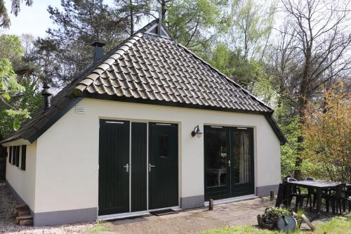 a small cottage with black doors and a table at Vakantiehuis de Witte Bergen in IJhorst