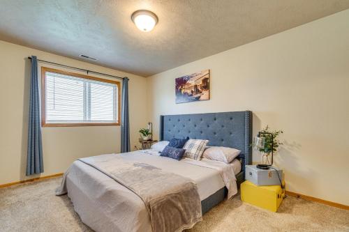 a bedroom with a bed with a blue headboard and a window at Cozy Sioux Falls House - Walk to Park! in Sioux Falls
