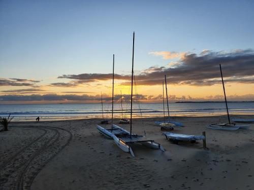 un grupo de barcos sentados en la playa al atardecer en Escale Côte d'Amour, en Pornichet