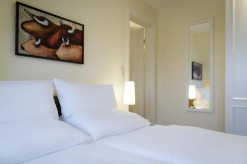 a white bed with two pillows in a bedroom at Hotel Aarnhoog in Keitum
