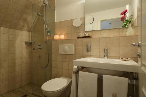 a bathroom with a toilet and a sink and a shower at Hotel Aarnhoog in Keitum