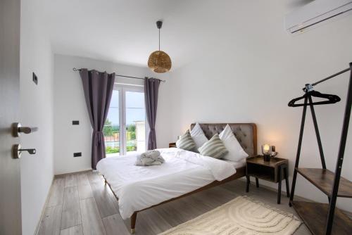 a white bedroom with a bed and a window at Villa Istra Pohman in Barat