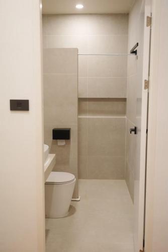 a white bathroom with a toilet and a shower at Daisy B in Hat Yai