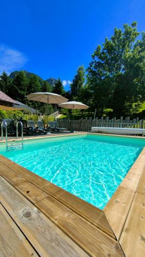 une grande piscine bleue avec une terrasse en bois dans l'établissement Le mazot d'H, à Entremont