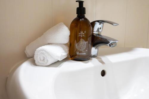 ein Waschbecken mit einer Flasche Seife und Handtüchern in der Unterkunft Le Doux Art de Vivre - Studio 2 personnes avec vue in Doussard