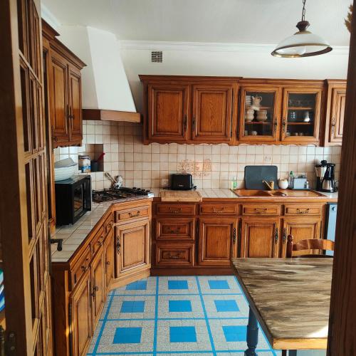 une cuisine avec des placards en bois et un tapis bleu dans l'établissement Chez Dom et Pascal, à Plestin-les-Grèves