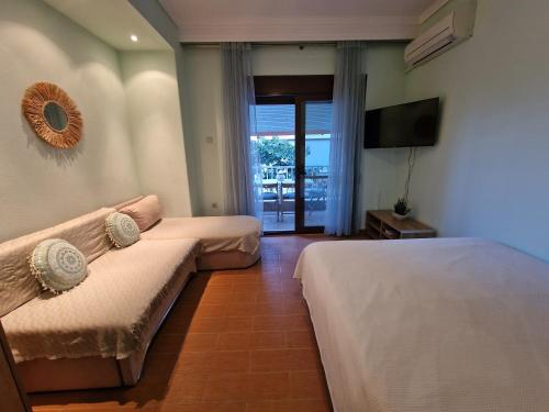a bedroom with a bed and a couch and a television at Pnoe Studios in Nea Moudania