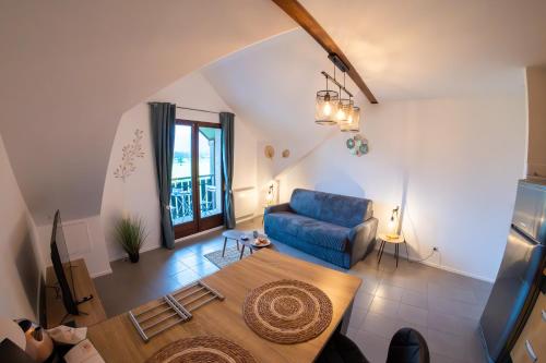 ein Wohnzimmer mit einem blauen Sofa und einem Tisch in der Unterkunft Le Doux Art de Vivre - Studio 2 personnes avec vue in Doussard