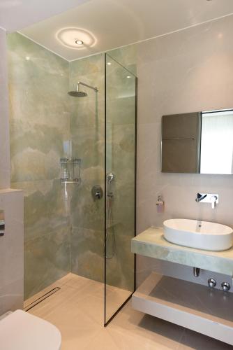 a bathroom with a glass shower and a sink at Anna Apartments in Chrysi Ammoudia