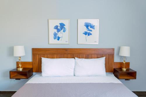 a bedroom with a bed with two lamps and two pictures at Casa La Martina Holbox in Holbox Island