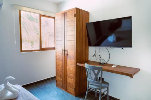 a bedroom with a desk with a tv and a chair at Casa La Martina Holbox in Holbox Island