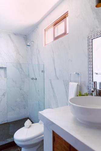 a white bathroom with a sink and a toilet at Casa La Martina Holbox in Holbox Island