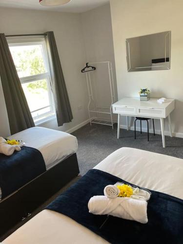 a room with two beds and a table with a window at Gemini 1 in Great Wyrley