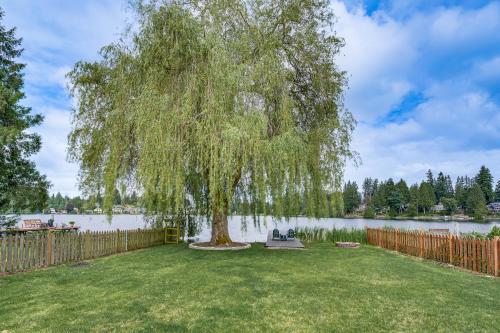 a weeping willow tree in a yard next to a fence at Lakefront Lynnwood Home with Balconies and Shared Dock in Lynnwood
