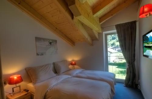 1 dormitorio con 2 camas blancas y ventana en Residenz Kitzblick by Kaprun Rentals, en Kaprun