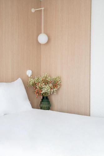 a vase filled with flowers sitting next to a bed at Novotel Macon Nord - Porte de Bourgogne in Mâcon
