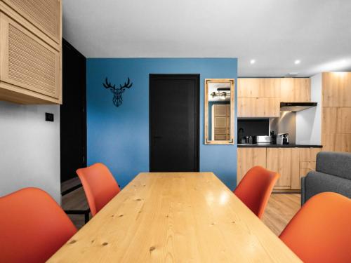 une salle à manger avec une table en bois et des chaises orange dans l'établissement Résidence Le Vanessa - maeva Home - Appartement chaleureux 2 pièces 4 personnes - Prestige - super Home MAE-7811, à Huez