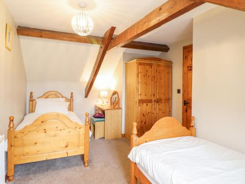 two beds in a bedroom with wooden beams at Llys-y-Wennol in Betws-y-coed