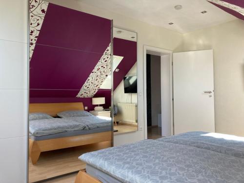a bedroom with a purple accent wall and two beds at Ferienwohnung Finkenschlag in Speyer
