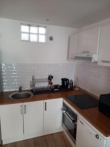 une cuisine avec des armoires blanches et un évier dans l'établissement Cosy Paris, à Paris