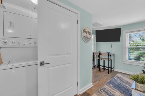 a white kitchen with a stove and a tv at 6-Min Walk to Asbury Park & OG Main St - Updated & Cozy Apartment in Historic Ocean Grove - Fire Pit & Patio - Fast Wi-Fi in Ocean Grove