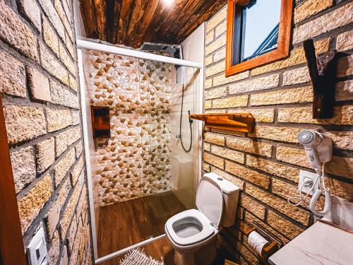 a bathroom with a brick wall and a toilet at Pousada Equilíbrio dos Canyons in Praia Grande