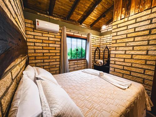 a bedroom with a bed in a brick wall at Pousada Equilíbrio dos Canyons in Praia Grande