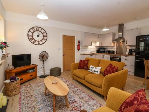 a living room with a yellow couch and a kitchen at Hardings cottage in Minehead