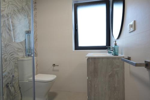 a bathroom with a toilet and a sink and a window at La casina de Tomás in Colunga