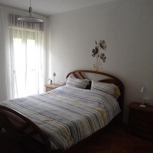 a bedroom with a bed with a wooden headboard and a window at la maison des fleurs in Fenis