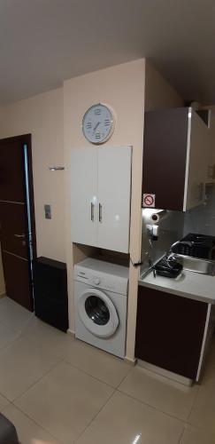 a kitchen with a washing machine and a clock on the wall at P & M Studio in Kavala